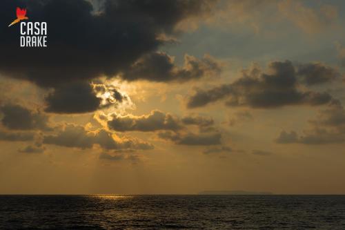 a cloudy sky over the ocean with the sun poking through at Casa Drake Lodge in Drake