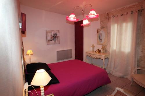 a bedroom with a pink bed and a table at Le Louvre - Lieu Atypique in Vauvert