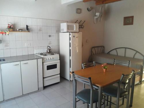 a kitchen with a table and a white refrigerator at Amaneceres Las Grutas in Las Grutas