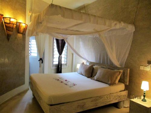 a bedroom with a white bed with a canopy at Lady D House in Watamu
