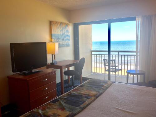 a bedroom with a bed and a television and a balcony at Ramada Plaza by Wyndham Virginia Beach Oceanfront in Virginia Beach