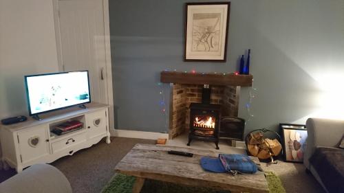 a living room with a fireplace and a television at Seaforth Cottage -Dog friendly, Historical Fishertown, central location in Nairn