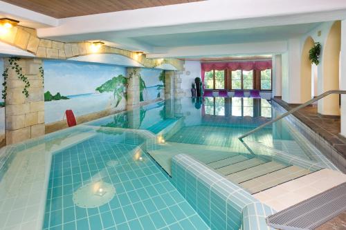 a swimming pool in a house with a painting on the wall at Ringhotel Nebelhornblick in Oberstdorf