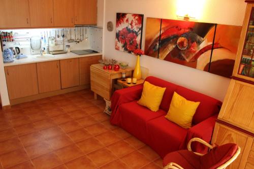 a living room with a red couch and a kitchen at Rose's House in Costa da Caparica