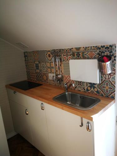 um balcão de cozinha com um lavatório e uma parede de azulejos em Cosy Attic City center em Lisboa