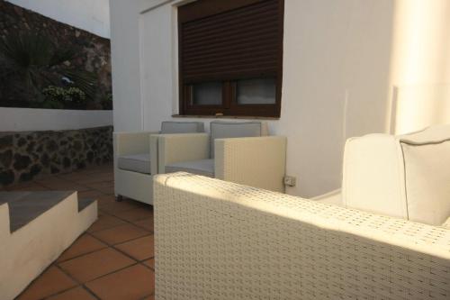 Un patio con sillas blancas y una ventana. en casa mira Vivienda vacacional, en Güime