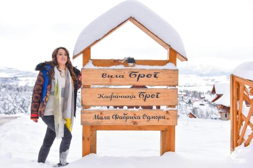 a woman standing next to a sign in the snow at Vila Breg Zlatibor in Zlatibor
