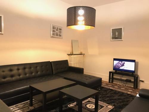 a living room with a couch and a tv at Luxury Suite Lilas 1 in Dijon
