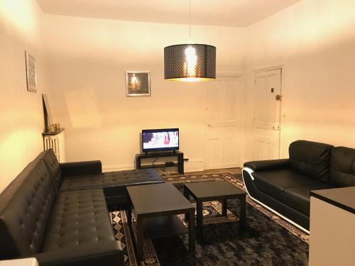 a living room with a couch and a tv at Luxury Suite Lilas 1 in Dijon