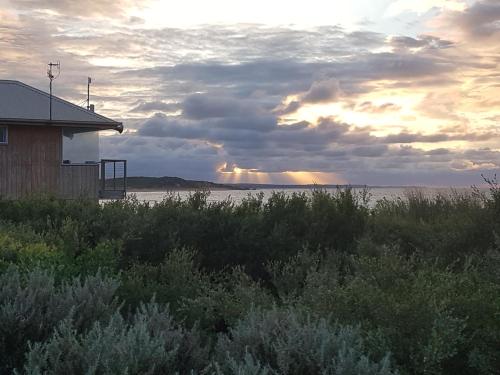 a sunset over the water with a building and a field at Wayamba in Warrnambool