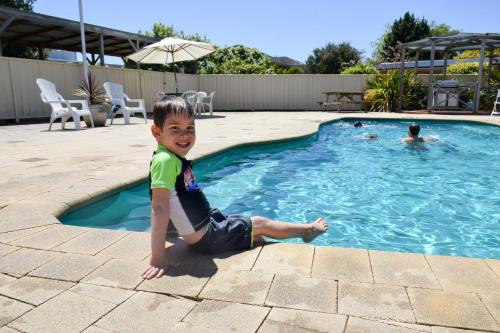 Ein kleiner Junge, der im Pool sitzt. in der Unterkunft Beachway Motel in Ulverstone