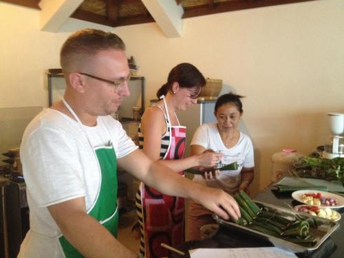 a man and two women in a kitchen preparing food at Puri Clinton Bali in Nusa Dua
