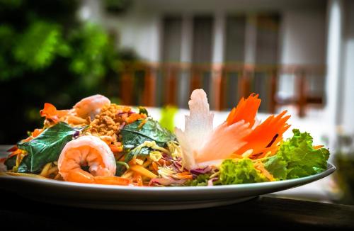 a plate of food with shrimp and vegetables on a table at Indra Angkor Residence in Siem Reap