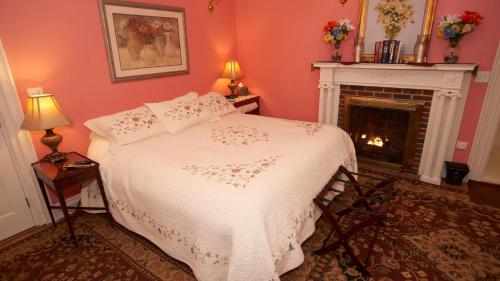 a bedroom with a white bed and a fireplace at Center Harbor Sutton House B & B in Center Harbor
