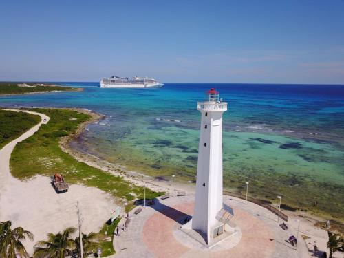 a lighthouse on the beach with a cruise ship in the background at Eco Cabañas Bluekay in Mahahual