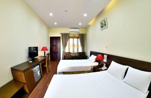 a hotel room with two beds and a television at Hanvet Hotel Do Son in Ðố Sơn