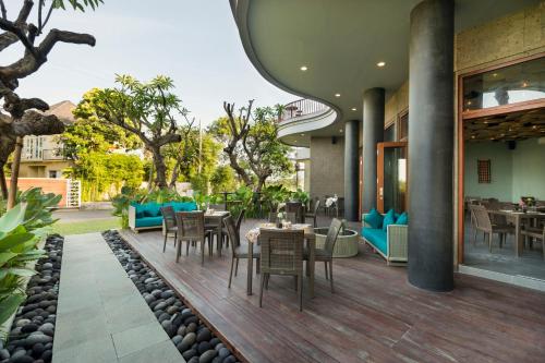 a restaurant with tables and chairs on a deck at Sense Canggu Beach Hotel in Canggu