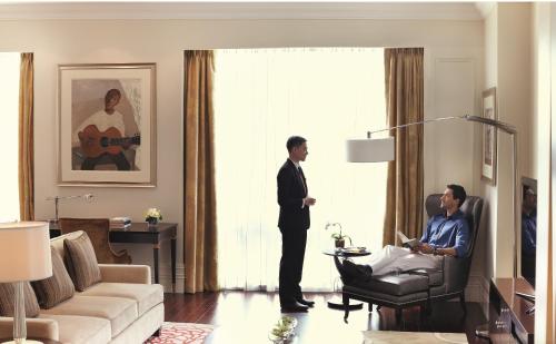 a man in a suit standing in a living room at Raffles Makati in Manila