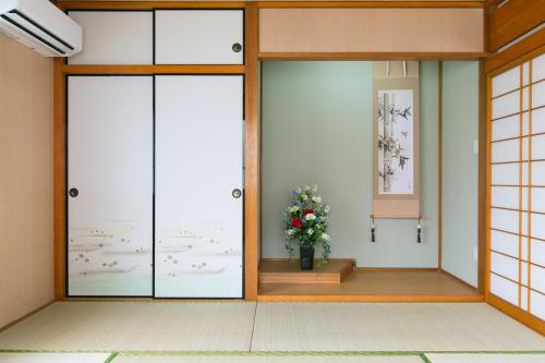 una habitación con dos puertas y un jarrón de flores en Okinawa Naha Nishi en Naha