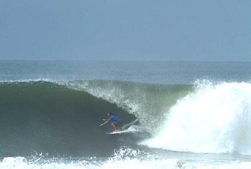 a man riding a wave on a surfboard in the ocean at Hotel Caleta in San Miguel