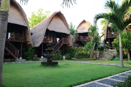 a resort with two thatched cottages with palm trees at MolaMola House in Nusa Lembongan