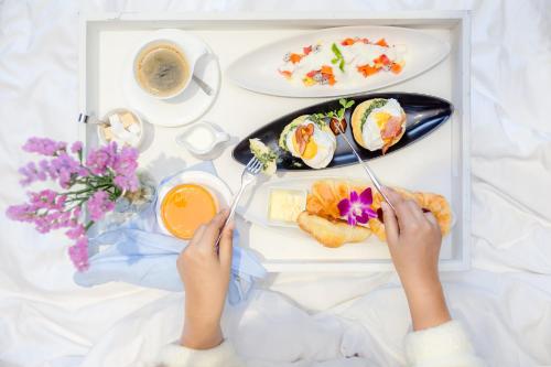 Eine Frau isst Essen aus einer Lunchbox in der Unterkunft Impiana Private Villas Kata Noi in Kata Beach