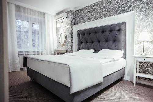 1 dormitorio con 1 cama grande y cabecero grande en Skif HOTEL & SPA en Petropavlovsk