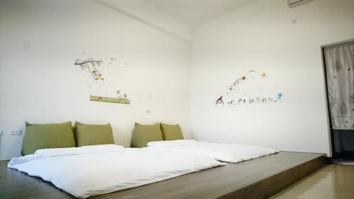 a bedroom with a bed with white sheets and green pillows at Sun Moon Star in Xinshe