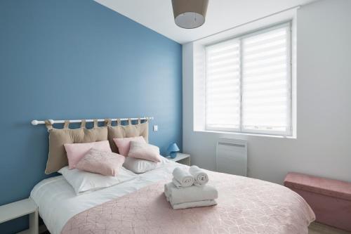 une chambre avec un grand lit avec des oreillers roses et blancs dans l'établissement Le Suroit by Cocoonr, à Saint-Malo