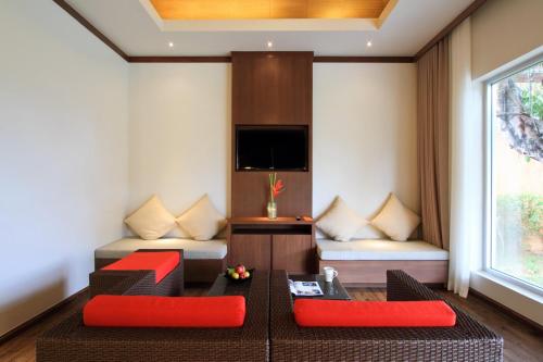 a living room with red furniture and a tv at Beyond Resort Khaolak - SHA Plus in Khao Lak