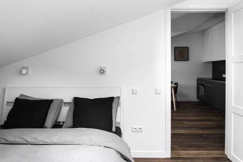 a white bedroom with a bed and a kitchen at Deluxe Apartments by Hostlovers in Kaunas