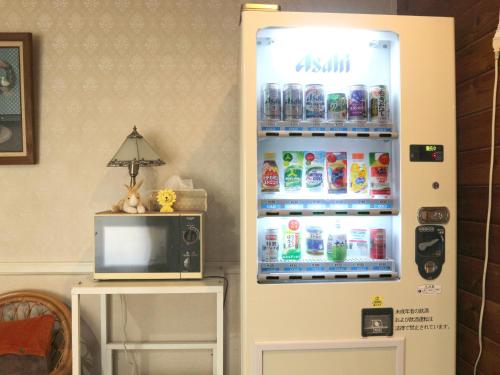 a refrigerator filled with drinks next to a microwave at Pension Eden in Naganohara