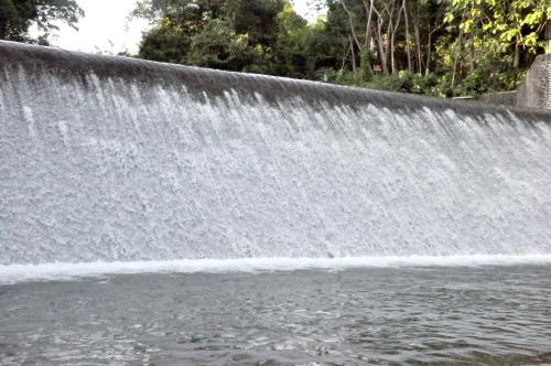 a waterfall on the side of a body of water at Hau Eco Lodges Citumang Pangandaran in Pangandaran