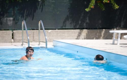 two people are swimming in a swimming pool at Long Beach Village Residence sul mare spiaggia privata inclusa in Lido Adriano
