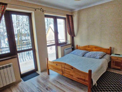 - une chambre avec un lit en bois et 2 fenêtres dans l'établissement Noclegi w centrum Sienkiewicza, à Zakopane