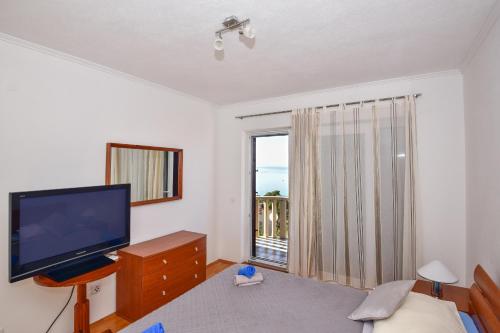 a bedroom with a television and a bed with a window at Apartments Mare in Brela