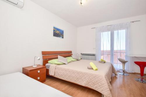 a white bedroom with a bed and a window at Apartments Mare in Brela