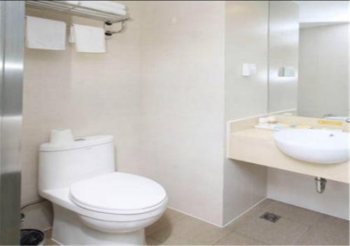 a white bathroom with a toilet and a sink at Goldmet Inn Chengdu Baiguolin underground Station in Chengdu