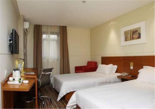ein Hotelzimmer mit 2 Betten und einem Schreibtisch in der Unterkunft Goldmet Inn Chengdu Baiguolin underground Station in Chengdu