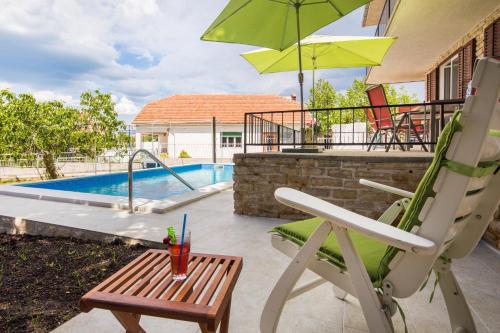 a patio with a chair and an umbrella and a pool at Villa Amalia in Murter