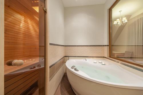 uma casa de banho com uma banheira grande e um espelho. em Kalnmuižas pils em Kalnmuiža