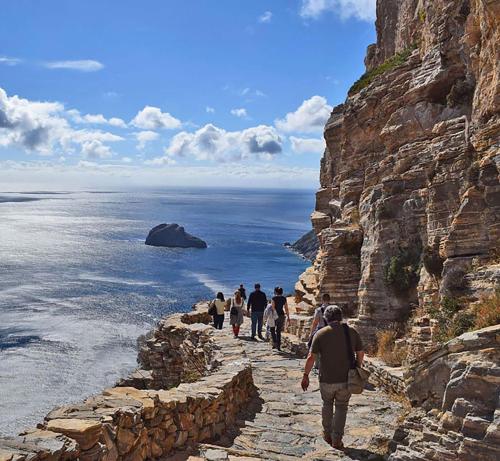 a group of people walking down a stone path near the ocean at Aegialis Hotel & Spa in Aegiali