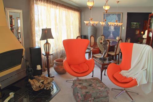 a living room with two orange chairs and a tv at Gîte Chez Baza in Shawinigan