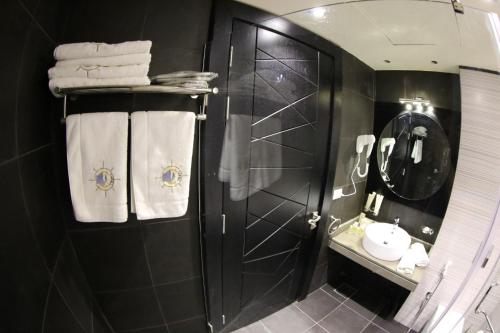 a bathroom with a shower and a sink and towels at Layali Al Shams Hotel in ‘Anjar