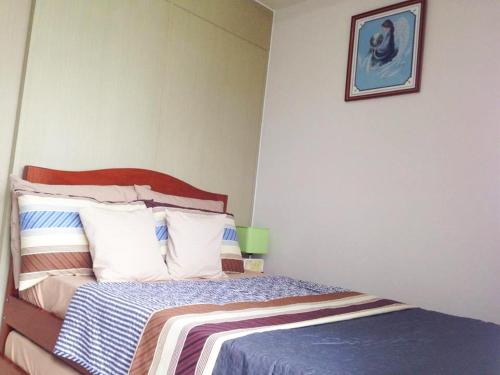 ein Schlafzimmer mit einem Bett und einem Bild an der Wand in der Unterkunft Hannah's Place at Wind Residences in Tagaytay