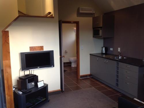 a room with a kitchen with a television and a bathroom at First Light Kaikoura in Kaikoura