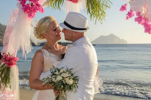 a bride and groom posing for a picture on the beach at Aegialis Hotel & Spa in Aegiali