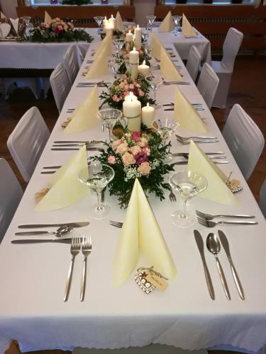 Una larga mesa blanca con velas y flores. en Hotel Rohanov, en Lhota nad Rohanovem