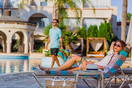 a woman laying on a lounge chair by a pool at Napa Plaza Hotel (Adults Only) in Ayia Napa