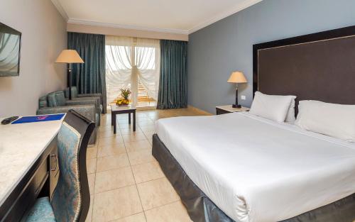 Habitación de hotel con cama grande y sala de estar. en Hawaii Caesar Palace Aqua Park - Families and Couples Only en Hurghada